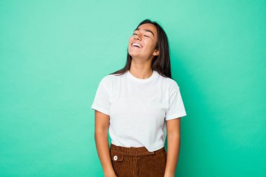 Genç melez Hintli kadın izole edilmiş rahat ve mutlu bir şekilde gülüyor, boynunda dişlerini gösteriyor..