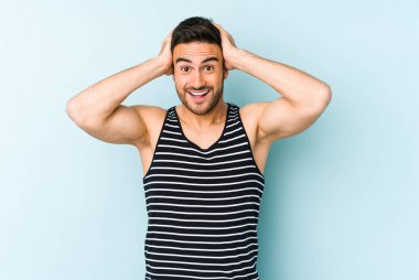 Genç beyaz adam mavi arka planda izole edilmiş bağırıyor, çok heyecanlı, tutkulu, bir şeyden memnun..