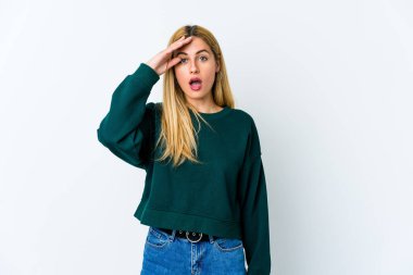 Beyaz arka planda izole edilmiş genç sarışın kadın yüksek sesle bağırıyor, gözleri açık ve elleri gergin tutuyor..