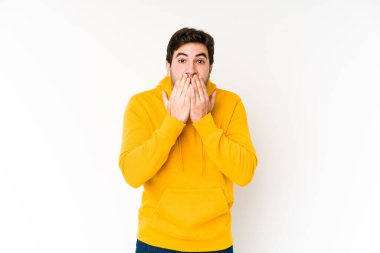 Beyaz arka planda izole edilmiş genç adam şok olmuş, ağzı ellerle kaplanmış, yeni bir şey keşfetmeye hevesli..