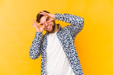 Sarı arka planda izole edilmiş genç beyaz adam gözlerinde sorun olmadığını gösteriyor.