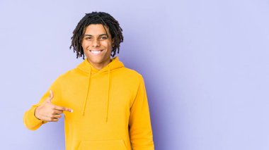 Afro-Amerikan Rasta 'lı genç bir adam gömleğin fotokopi odasını elle gösteriyor, gururlu ve kendinden emin.