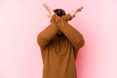 Pembe arka planda izole genç beyaz adam iki kolu çapraz tutuyor, inkar kavramı.