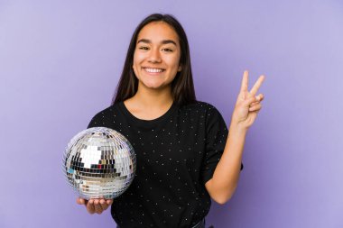 Bir balo düzenleyen Asyalı genç kadın neşeli ve kaygısız bir şekilde parmaklarıyla barış sembolü gösteriyor..