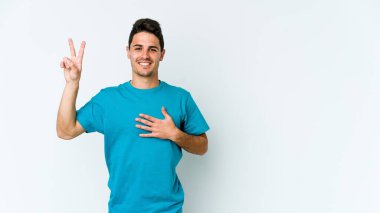 Beyaz arka planda izole edilmiş genç beyaz adam yemin ediyor, elini göğsüne koyuyor..