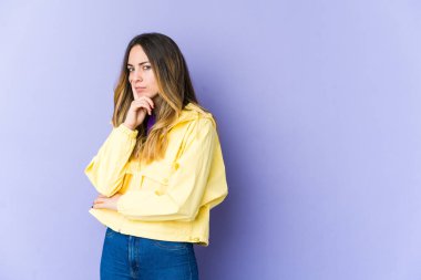 Mor arka planda izole edilmiş beyaz bir kadın mutsuz bir şekilde alaycı bir ifadeyle kameraya bakıyor..