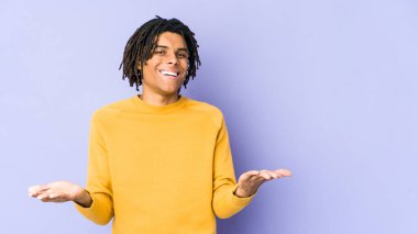 Rasta saç stili giyen genç siyah adam kollarıyla ölçeği yapıyor, mutlu ve kendinden emin hissediyor..