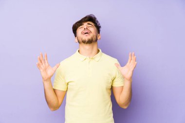 Mor arka planda izole edilmiş genç bir Arap gökyüzüne haykırıyor, yukarı bakıyor, hayal kırıklığına uğruyor..