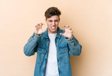 Beyazlı genç bir adam bej arka planda izole edilmiş pençelerini kedi taklidi yaparken gösteriyor, agresif bir hareket..