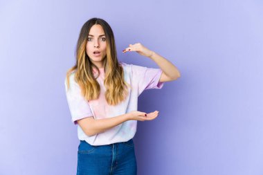 Mor arka planda izole edilmiş genç beyaz kadın elleri arasında bir kopya alanı tutarken şok ve şaşkınlık yaşadı..