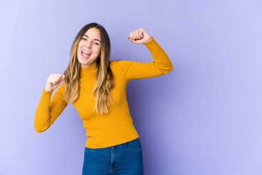 Mor arka planda izole edilmiş genç beyaz kadın dans ediyor ve eğleniyor..