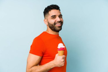 Dondurma tutan genç latin adam, yalnız görünüyor, gülümsüyor ve keyifli..