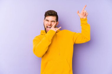 Mor arka planda yaşayan genç adam dans ediyor ve eğleniyor..