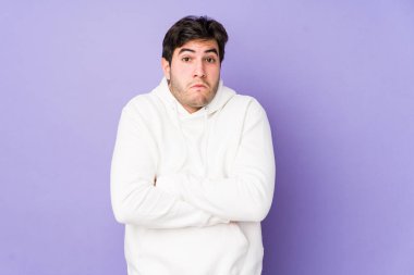 Mor arka planda soyutlanmış genç bir adam omuzlarını silker ve gözleri açık kalır..