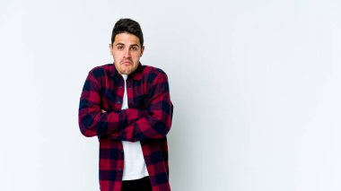 Beyaz arka planda izole edilmiş genç beyaz bir adam omuz silkiyor ve gözleri açık..