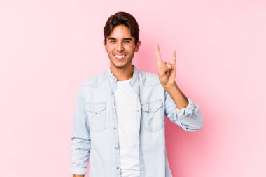 Pembe arka planda poz veren genç, beyaz bir adam boynuzlarını devrim konsepti olarak gösteriyor..