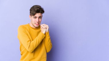 Mor arka planda izole edilmiş genç beyaz adam korkmuş ve korkmuş..