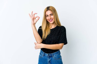 Beyaz arka planda izole edilmiş genç sarışın bir kadın bir göz kırptı ve elleriyle iyi bir jest yaptı..