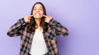 Genç, melez, ispanyol bir kadın. Tek başına gülüyor, parmaklarını ağzına doğrultuyor..