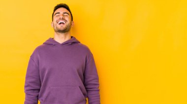 Kafkasyalı genç adam sarı fırında izole edilmiş gevşemiş ve mutlu bir şekilde gülüyor, boynunda dişlerini gösteriyor..