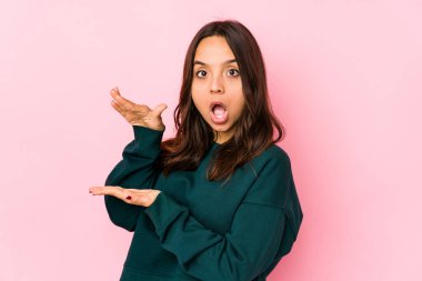 Latin kökenli genç bir kadın şok olmuş ve hayrete düşmüş. Ellerinin arasında bir kopya alanı tutuyor..