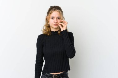 Beyaz arka planda beyaz tenli genç bir kadın parmakları dudaklarında bir sır saklıyor..