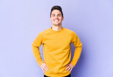 Mor arka planda izole edilmiş beyaz bir adam. Kendine güveniyor. Kalçaları tutuyor..