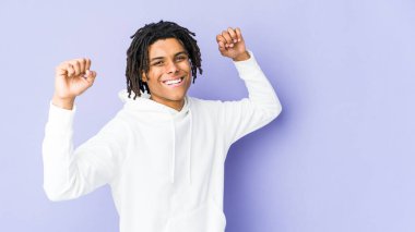 Genç Afrikalı Amerikalı Rasta adam özel bir günü kutluyor, atlıyor ve enerjiyle kollarını kaldırıyor..