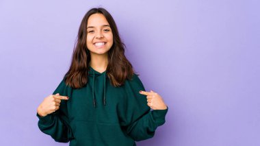 Genç, Latin kökenli bir kadın tişört fotokopi alanını elle işaret ediyor, gururlu ve kendinden emin.