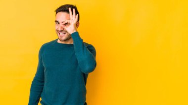 Kafkasyalı genç adam sarı fırında izole edilmiş. Heyecanlı. Göze göz hareketi yapıyor..