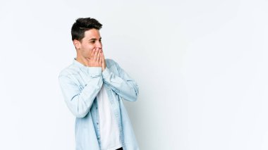 Beyaz arka planda izole olmuş genç beyaz bir adam bir şeye gülüyor, ağızlarını ellerle kapatıyor..