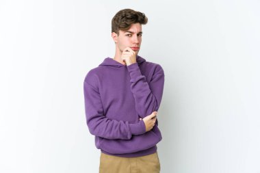 Beyaz arka planda izole edilmiş genç beyaz bir adam şüpheli, belirsiz, seni muayene ediyor..