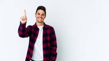 Beyaz arka planda izole edilmiş beyaz tenli genç bir adam bir numarayı parmağıyla gösteriyor..