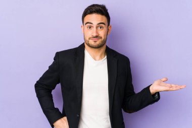 Mor arka planda izole edilmiş genç beyaz bir adam bir avuç içinde fotokopi alanı ve belinde bir el daha gösteriyor..