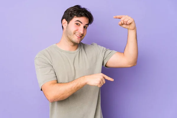 Ung Man Isolerad Lila Bakgrund Hålla Något Lite Med Pekfingrar — Stockfoto