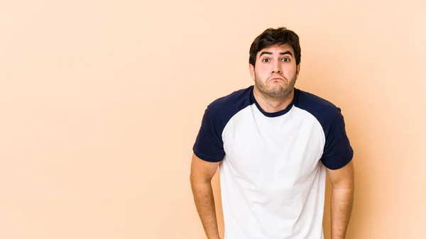 Young Man Isolated Beige Background Shrugs Shoulders Open Eyes Confused — Stock Photo, Image