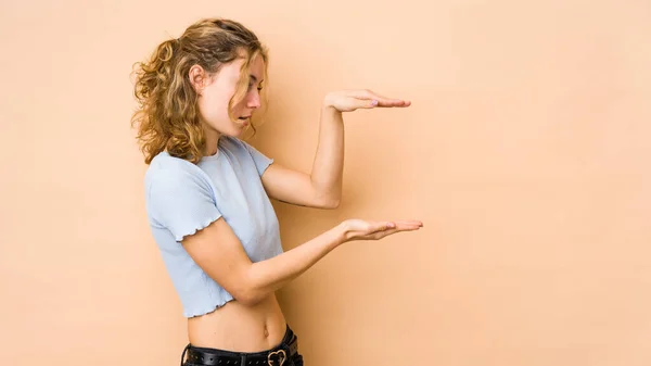 Ung Kaukasisk Kvinna Isolerad Beige Bakgrund Chockad Och Förvånad Hålla — Stockfoto