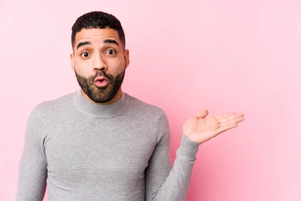 stock image Young latin man against a pink background isolated impressed holding copy space on palm.