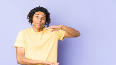 Genç Afrikalı Amerikalı Rasta adam iki eliyle bir şey tutuyor, ürün sunumu..