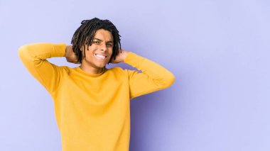 Rasta saç stili giyen genç siyahi adam kafasının arkasına dokunuyor, düşünüyor ve bir seçim yapıyor..