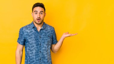 Sarı fırında izole edilmiş genç beyaz adam, avuç içinin fotokopi alanını elinde tutmaktan etkilendi..