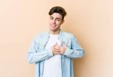 Beyazların arka planında izole edilmiş genç beyaz bir adam dost ifadesine sahip, avuçlarını göğsüne bastırıyor. Aşk konsepti.