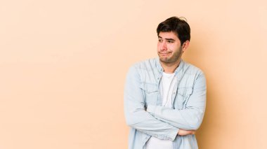 Bej arka planda izole edilmiş genç adam kafası karışmış, şüpheli ve güvensiz hissediyor..