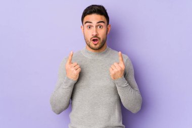 Mor arka planda izole edilmiş beyaz bir adam ağzı açık bir şekilde üst tarafı işaret ediyor..