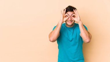 Bej arka planda izole edilmiş genç adam gözlerde sorun olmadığını gösteriyor.