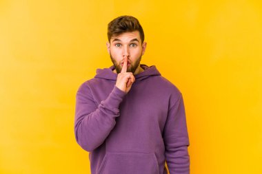 Sarı arka planda izole edilmiş genç beyaz bir adam ya sır saklıyor ya da sessizlik istiyor..