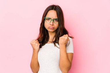 Genç, melez İspanyol kadın kameraya yumruk gösteriyor, agresif bir yüz ifadesi var..