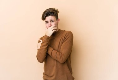 Beyazlı genç adam bej arka planda izole edilmiş korkmuş ve korkmuş..