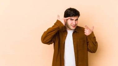 Bej arka planda izole edilmiş genç bir adam işaret parmağıyla bir hayal kırıklığı gösteriyor..