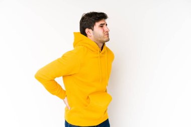 Genç adam beyaz arka planda izole edilmiş, sırt ağrısı çekiyor..